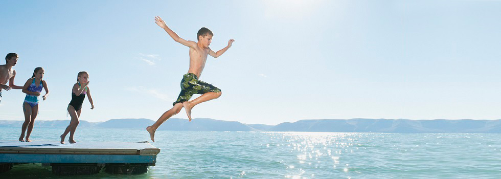 Kinder springen von Ponton-Badeinsel in den See
